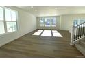 Spacious living room with wood floors, white walls, large windows, and a staircase leading to the upper floor at 5546 Inland Ave, Firestone, CO 80504