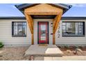 Close up of home's front door with natural wood entry covering, plants, and minimalist rock yard at 5362 S Cedar St, Littleton, CO 80120