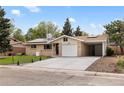 Inviting home exterior featuring a well-manicured lawn, solar panels, attached garage and carport at 5329 Flower Cir, Arvada, CO 80002