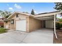 Side view of a brick home showcasing a driveway, garage, and attached carport at 5329 Flower Cir, Arvada, CO 80002