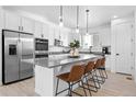 Bright kitchen featuring white cabinetry, stainless steel appliances, a large island and leather counter stools at 12261 Farmview St, Thornton, CO 80241