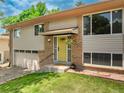 Inviting home exterior featuring a sunny yellow door, brick detail, and lush green lawn at 1811 S Yank Ct, Lakewood, CO 80228