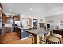 Open-concept kitchen with granite countertops, island seating, and stainless steel appliances flowing into the living area at 15502 E Flower Mound Pl, Parker, CO 80134