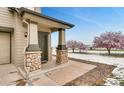 Welcoming front porch with stone-clad columns and a well-maintained entrance; lovely flowering trees in the yard at 12914 Grant Cir # C, Thornton, CO 80241