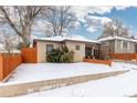 View of backyard with snow covering the ground, complimented by wooden fence and shrubbery at 3130 S Washington St, Englewood, CO 80113
