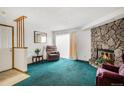 Cozy living room featuring a stone fireplace, plush carpeting, and natural light at 15350 E Arizona Ave # 106, Aurora, CO 80017