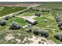 Aerial view showcasing a brown home and large shop, complemented by lush green landscape and clear skies at 68251 E 96Th Ave, Byers, CO 80103