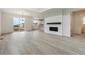 Bright, open-concept living room with fireplace, light wood floors, and seamless flow to the kitchen at 9243 Truckee Ct, Commerce City, CO 80022