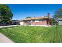 Classic brick home with a lush green lawn, bright accents, and timeless architectural charm at 392 Central Ave, Brighton, CO 80601