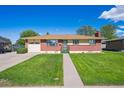 Inviting single-story home with a brick facade, manicured lawn, and convenient driveway access at 392 Central Ave, Brighton, CO 80601