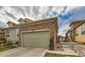 Home featuring a two-car garage with a stone facade and well-maintained landscaping at 12715 Madison St, Thornton, CO 80241