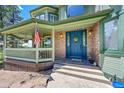 Inviting front porch featuring brick accents, an American flag and a stylish door at 6681 Flintwood Rd, Parker, CO 80138