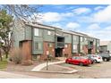 Well-maintained condo exterior with brick accents, wood siding, manicured landscaping, and ample parking spaces at 3546 S Depew St # 103, Denver, CO 80235