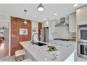 Well-lit kitchen shows a spacious island, stainless steel appliances, and exposed brick accent wall at 4036 Navajo St, Denver, CO 80211