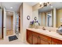 Well-lit bathroom with wood vanity, single sink, neutral tile, and walk in shower at 9298 Spirit Ct, Parker, CO 80138