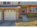Close up view of home's brick facade, front entrance and two-car garage at 13294 W 65Th Dr, Arvada, CO 80004