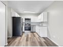 Well-lit kitchen featuring stainless appliances, white cabinetry, stone countertops, and wood-look floors at 795 S Alton Way # 11C, Denver, CO 80247