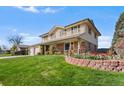 Beautiful two-story house with a brick and siding exterior, green lawn, and vibrant flower beds at 3191 S Holly Pl, Denver, CO 80222