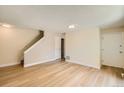 Bright living room features wood-look flooring, neutral paint, and convenient access to stairs and doors at 8039 Wolff St # E, Westminster, CO 80031