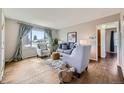 Bright living room featuring hardwood floors, a large window with curtains, and neutral-toned furniture with stylish accents at 1701 W 50Th Ave, Denver, CO 80221