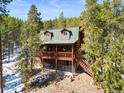 Charming multi-story cabin with a green roof and a spacious wooden deck surrounded by lush trees at 456 Copperdale Ln, Golden, CO 80403