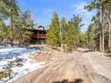 Scenic view of a multi-story cabin with a green roof and a wooden deck along a rustic dirt road at 456 Copperdale Ln, Golden, CO 80403