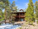 Scenic view of a multi-story cabin with a green roof and a wooden deck surrounded by lush trees at 456 Copperdale Ln, Golden, CO 80403
