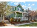 Beautiful two-story home with a covered porch, green exterior paint, and a well-manicured lawn at 3178 Geneva Ct, Denver, CO 80238