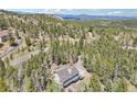 Aerial view of a mountainside house surrounded by lush forest and scenic mountain views at 10469 Christopher Dr, Conifer, CO 80433