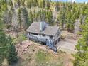 A view of the house with a deck surrounded by trees, situated on a mountainside at 10469 Christopher Dr, Conifer, CO 80433