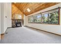 Bright living room with wood ceilings, stone fireplace, and a view of the outdoors from large windows at 10469 Christopher Dr, Conifer, CO 80433
