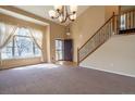 Inviting living room features plush carpet, high ceilings, and a grand staircase at 6786 Silverleaf Ave, Firestone, CO 80504