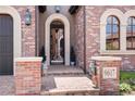 Elegant front entrance with brick facade, arched gate, decorative lanterns, and visible house number at 9617 S Shadow Hill Cir, Lone Tree, CO 80124