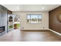 Bright living room with modern fireplace, hardwood floors, and a large window showcasing the front yard at 2840 Cottonwood Dr, Denver, CO 80221