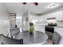 Bright kitchen with white cabinetry, stainless steel appliances, complemented by a round dining table and staircase at 8905 Field St # 91, Westminster, CO 80021