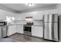 Modern kitchen with white cabinets, stainless steel appliances, granite countertops, and wood-look flooring for a sleek design at 8905 Field St # 91, Westminster, CO 80021