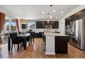 Modern kitchen with dark cabinets, granite countertops, stainless steel appliances, and an island with bar seating open to dining area at 655 Tiger Lily Way, Highlands Ranch, CO 80126