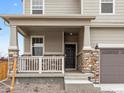 Inviting covered front porch with stone pillars and railing at 8840 Sedalia St, Commerce City, CO 80022