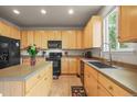 Bright kitchen featuring light wood cabinets, black appliances, a center island, and a window at 11373 Kearney Way, Thornton, CO 80233