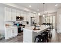 Bright kitchen featuring white cabinets, stainless steel appliances, and a large island with bar seating at 6737 S Tempe Ct, Aurora, CO 80016