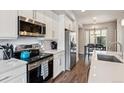 Modern kitchen boasts stainless steel appliances, white cabinets, and sleek countertops at 6737 S Tempe Ct, Aurora, CO 80016