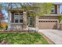 Charming two-story home featuring a stone-accented porch and well-manicured lawn at 12616 Jersey W Cir, Brighton, CO 80602
