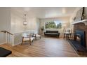 Open-concept living room featuring a fireplace, hardwood floors and natural light from the large window at 29691 Fairway Dr, Evergreen, CO 80439