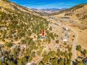 An aerial view showcases a hillside property nestled amongst pine trees with mountain views at 312 Meadow View Dr, Evergreen, CO 80439