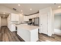 Bright kitchen features white cabinets, stainless appliances, and an island with a stone countertop at 523 Beckwourth Ave, Fort Lupton, CO 80621
