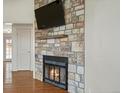 Cozy living room with a striking stone fireplace, hardwood floors, and a mounted television at 2433 E 90Th Ave, Thornton, CO 80229
