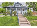 Charming light blue home featuring a well-manicured lawn, stone steps leading to the front porch, and beautiful landscaping at 3396 S Logan St, Englewood, CO 80113
