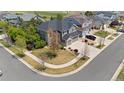 Aerial view of a gray home with a three car garage in a neighborhood with green grass and walking paths at 15915 E Summit Fox Ave, Parker, CO 80134