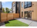 Modern home's backyard with a wooden fence, small grass area, concrete patio, and a sliding glass door entrance at 1262 N Stuart St # 2, Denver, CO 80204