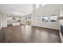 Bright living room featuring hardwood floors, high ceilings, large windows, and an open-concept kitchen at 16633 W 93Rd Way, Arvada, CO 80007